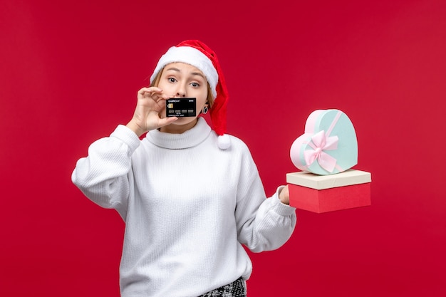 Front view young female with bank card and gifts on red desk