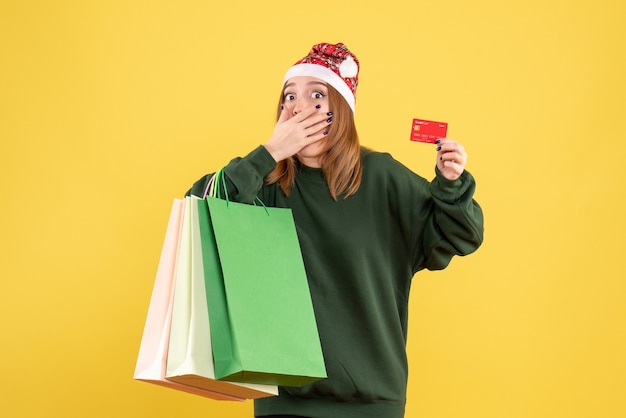 Молодая женщина вид спереди с банковской картой и пакетами покупок
