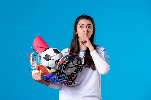 Free photo front view young female with basket full of sport things blue wall