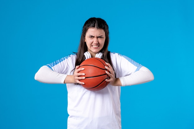 Free photo front view young female with basketball on blue wall