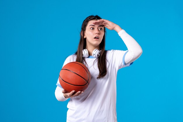 Front view young female with basketball on blue wall