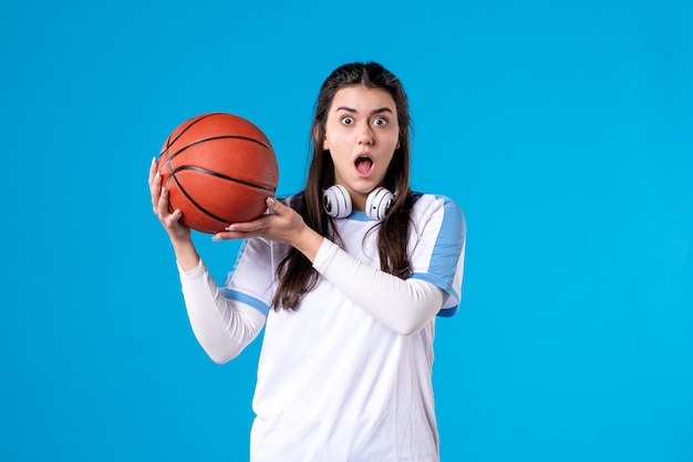 青い壁にバスケットボールと正面図若い女性