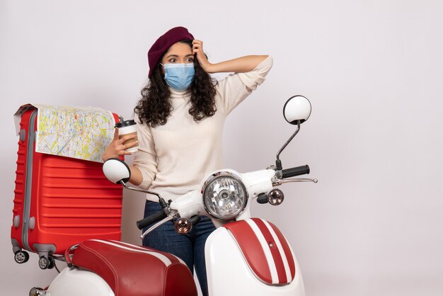 Front view young female with bike holding coffee on white background color covid- pandemic motorcycle flight virus speed vehicle