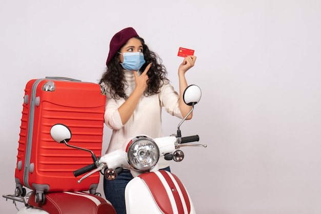 Front view young female with bike holding red bank card on white background color covid- vehicle virus pandemic motorcycle speed road