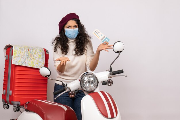 Front view young female with bike holding ticket on a white background color covid- vehicle virus pandemic motorcycle speed flight