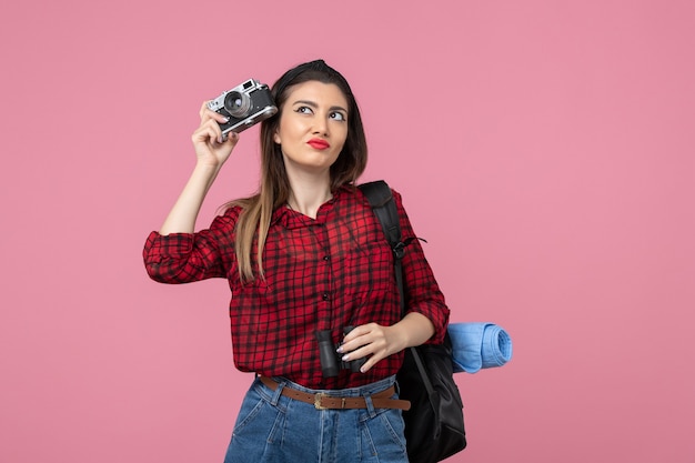 Front view young female with binoculars and camera on a pink background color woman human