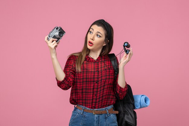 Front view young female with binoculars and camera on a pink background human color woman