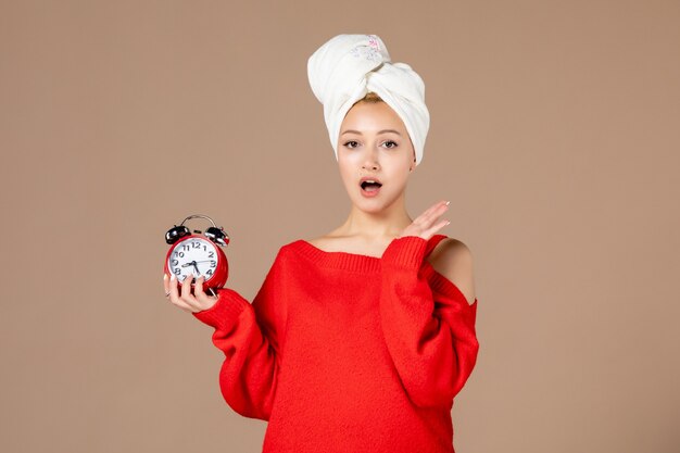 front view young female with clock and towel on her head on pink background