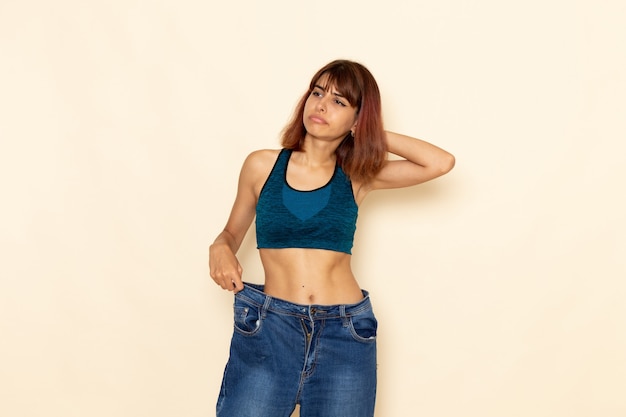 Free photo front view of young female with fit body in blue shirt checking her weight on the light white wall