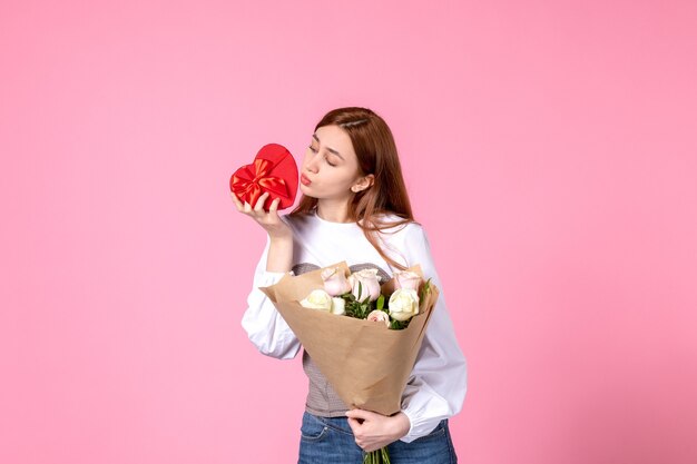 Вид спереди молодая женщина с цветами и подарок на женский день на розовом фоне горизонтальное равенство марша женское свидание женщина любовь чувственная