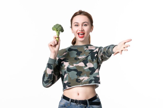 Front view young female with green broccoli on white background diet health food lunch horizontal colours meal body