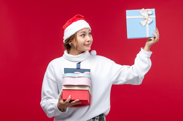Вид спереди молодая женщина с праздничными подарками на красном фоне