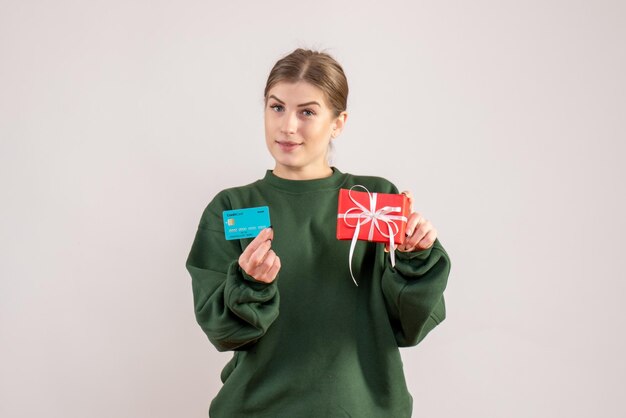 Вид спереди молодая женщина с маленьким подарком на рождество и банковской картой