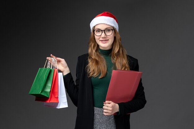 暗い壁のギフト新年クリスマスプレゼントのパッケージと正面図若い女性