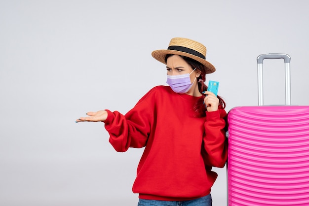 Front view young female with pink bag holding bank card in mask on white wall