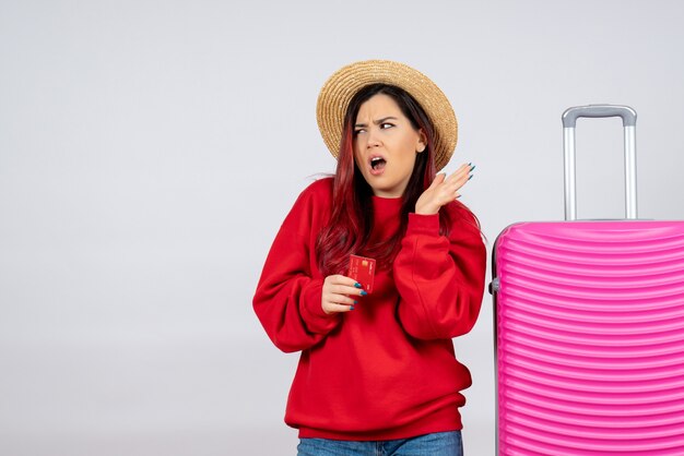 Front view young female with pink bag holding bank card on a white wall