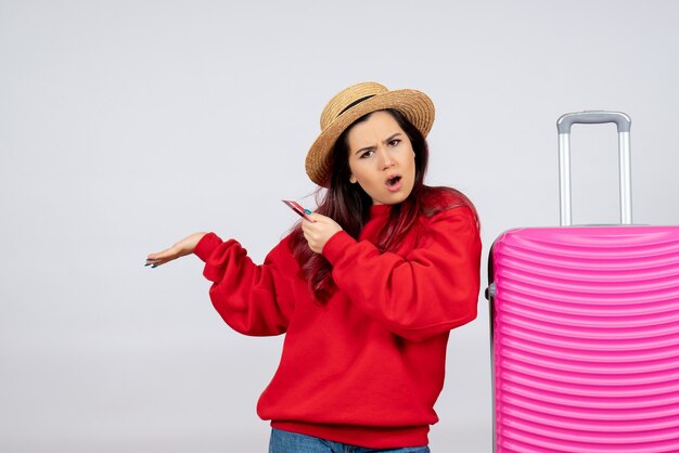 Front view young female with pink bag holding bank card on a white wall