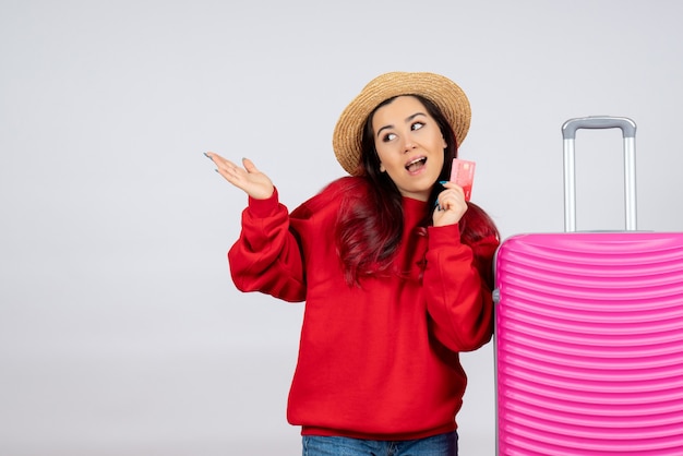 Вид спереди молодая женщина с розовой сумкой, держащей банковскую карту на белой стене