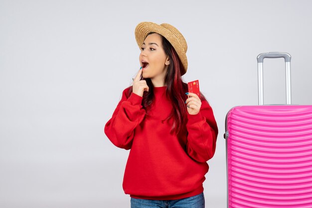 Вид спереди молодая женщина с розовой сумкой, держащей банковскую карту на белой стене
