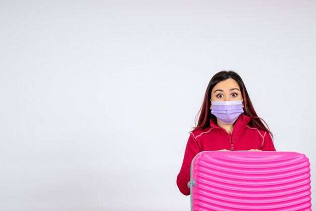 Front view young female with pink bag in mask on white wall vacation pandemic virus woman covid- color trip