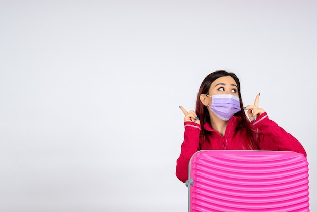 Front view young female with pink bag in mask on white wall virus vacation covid color pandemic trip