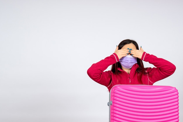 Front view young female with pink bag in mask on white wall virus woman vacation covid pandemic trip