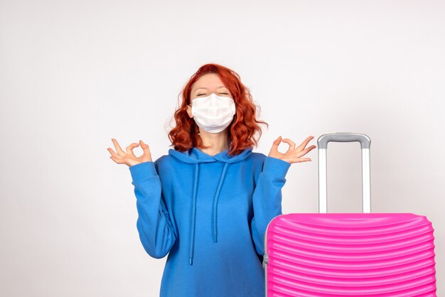 Foto gratuita vista frontale della giovane donna con borsa rosa in maschera sul muro bianco