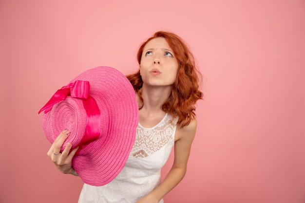 Front view of young female with pink hat on a pink wall