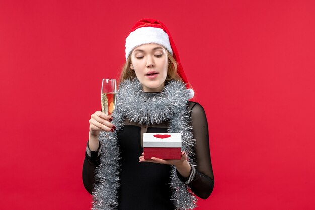 Front view young female with present celebrating on red wall holidays christmas color