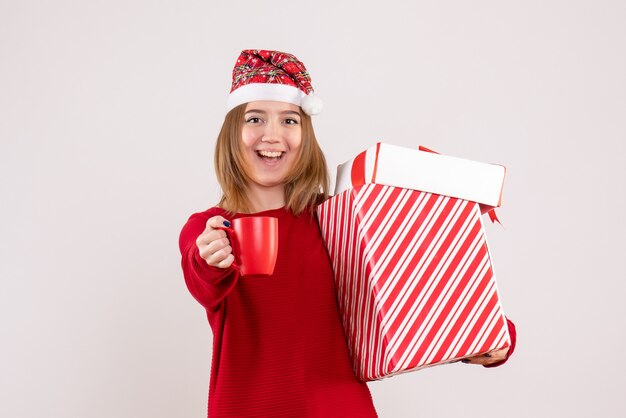プレゼントとお茶のカップを持つ若い女性の正面図