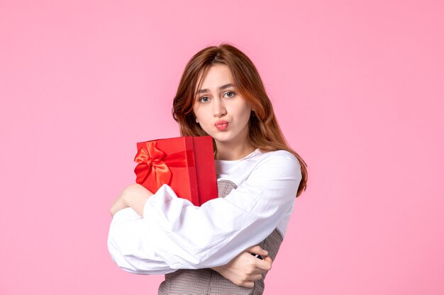 Front view young female with present in red package on pink background date march horizontal love woman sensual equality