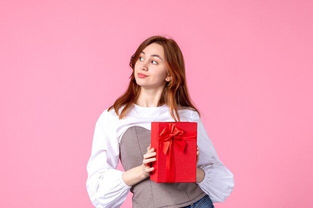 Front view young female with present in red package on pink background love date march horizontal gift perfume woman photo money equality