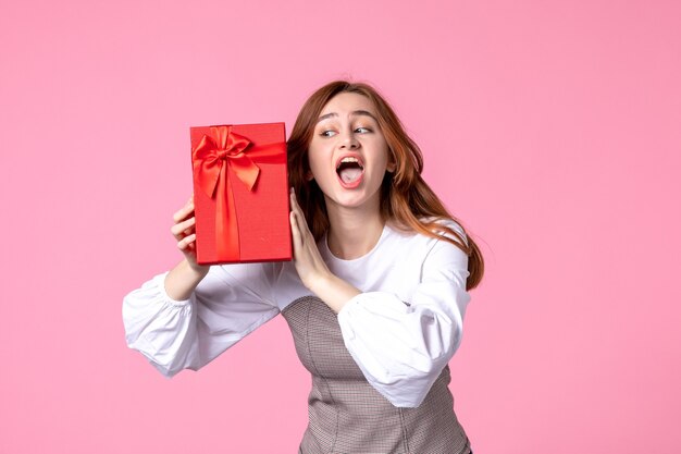 Front view young female with present in red package on pink background love date march horizontal sensual gift equality woman photo money