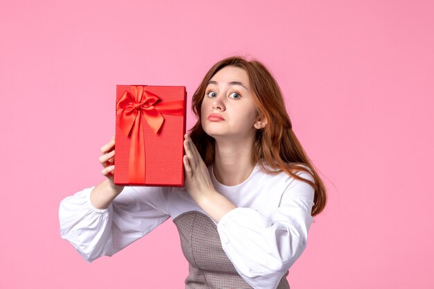 Front view young female with present in red package on pink background love date march horizontal sensual gift perfume equality photo money