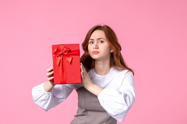 Front view young female with present in red package on pink background love date march horizontal sensual gift perfume equality woman photo