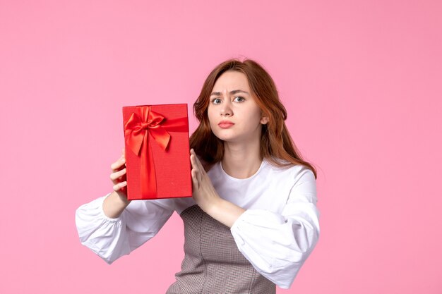 ピンクの背景に赤いパッケージでプレゼントと正面図若い女性愛の日付行進水平官能的なギフト香水平等女性の写真
