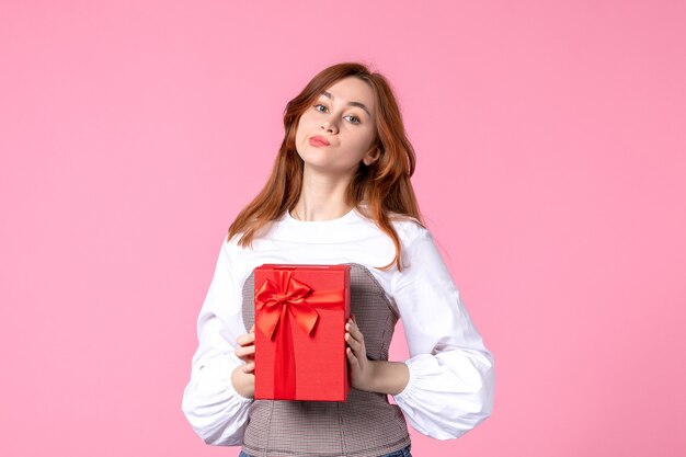 Front view young female with present in red package on pink background love date march horizontal sensual gift perfume woman photo equality