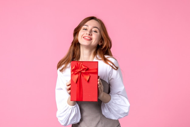 Front view young female with present in red package on pink background love date march horizontal sensual gift perfume woman photo money equality