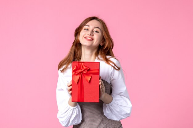 Front view young female with present in red package on pink background love date march horizontal sensual gift perfume woman photo money equality