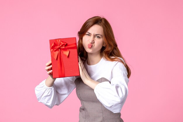 Front view young female with present in red package on pink background love date march horizontal sensual gifts perfume equality woman photo money