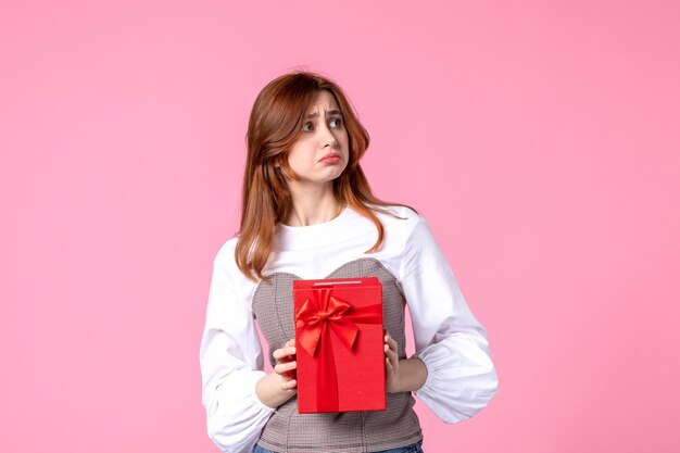 Front view young female with present in red package on pink background march horizontal sensual gift perfume photo money woman