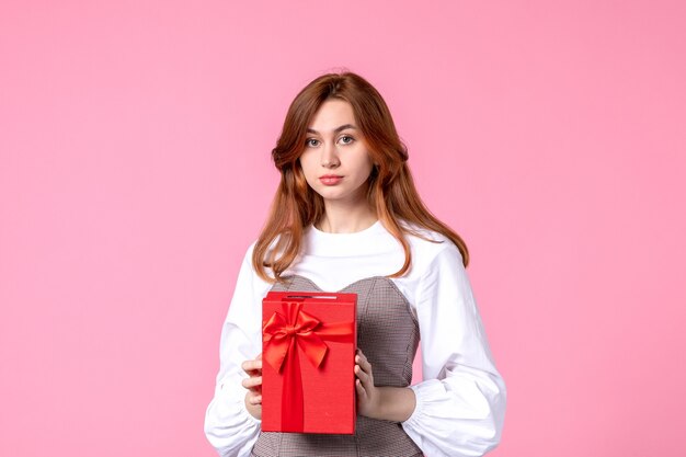 Front view young female with present in red package on pink background march horizontal sensual gift perfume photos money equality woman