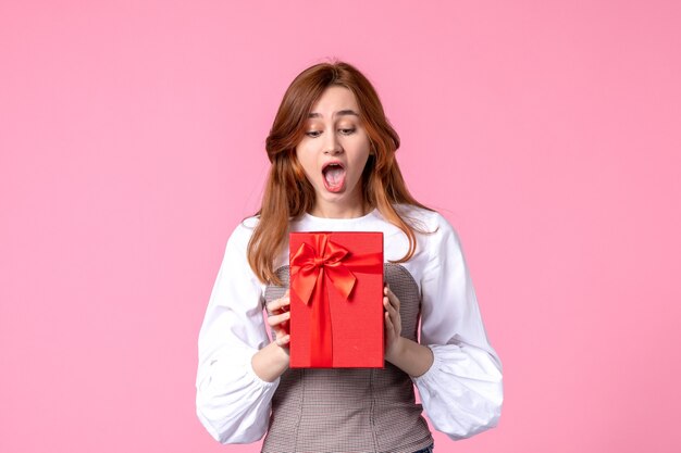 Front view young female with present in red package on pink background march horizontal sensual gift photo money equality woman perfume