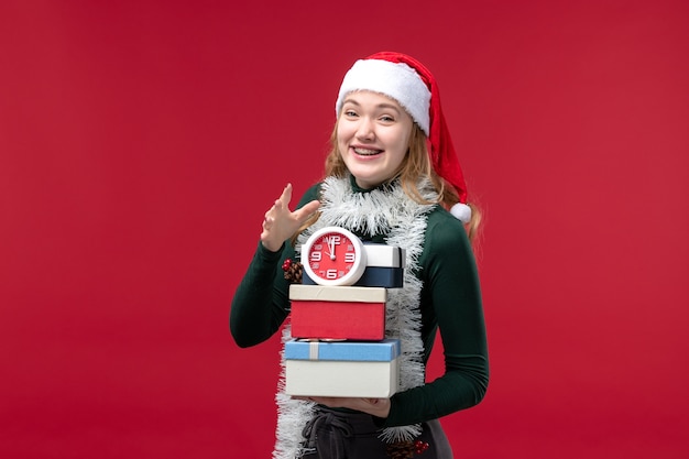 Front view young female with presents with clock on light red background