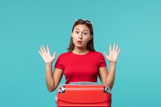 Front view young female with red bag getting ready for vacation on blue desk