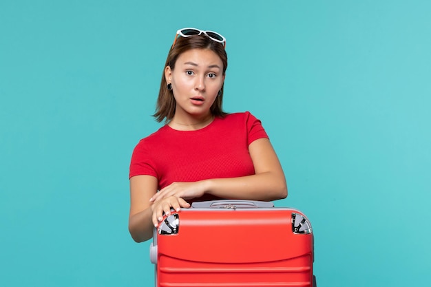 파란색 책상에 휴가를 준비하는 빨간 가방 전면보기 젊은 여성