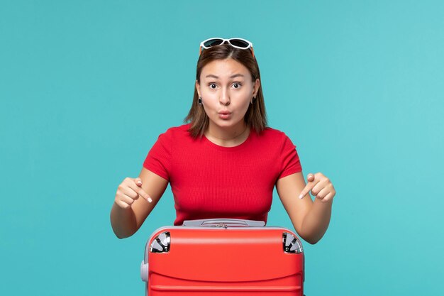 Front view young female with red bag getting ready for vacation on a blue space