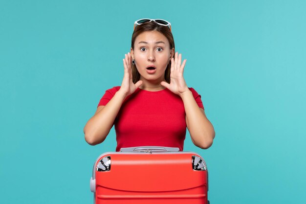 Front view young female with red bag getting ready for vacation on light blue space