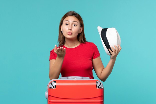 Front view young female with red bag holding her hat on light blue space