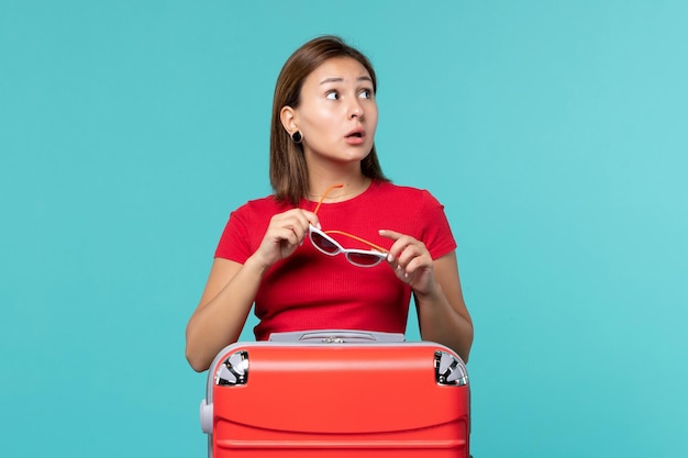 Front view young female with red bag holding her sunglasses on the blue space